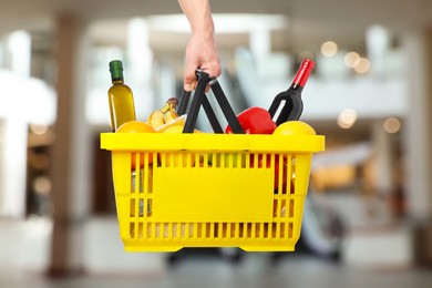 Image of Man holding shopping basket with different food products at supermarket, closeup