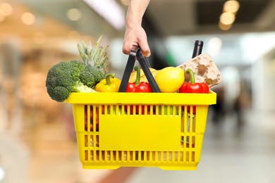Image of Man holding shopping basket with different food products at supermarket, closeup