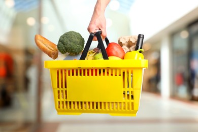 Image of Man holding shopping basket with different food products at supermarket, closeup