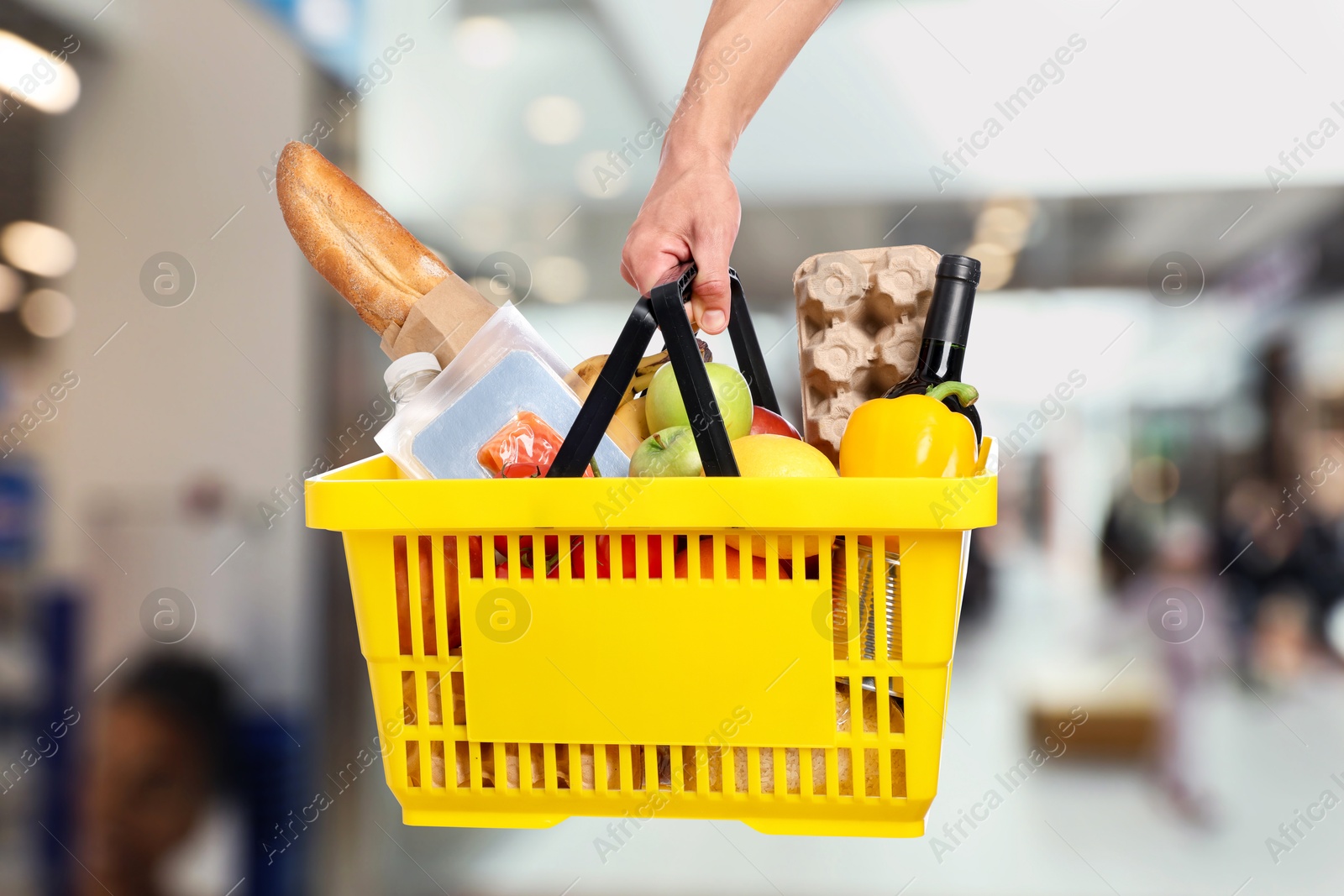 Man holding shopping basket with different food products at supermarket, closeup Image of Man holding shopping basket with different food products at supermarket, closeup