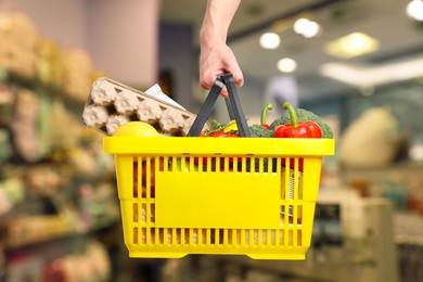 Image of Man holding shopping basket with different food products at supermarket, closeup