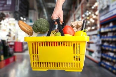 Image of Man holding shopping basket with different food products at supermarket, closeup
