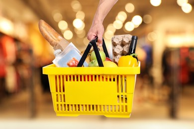 Image of Man holding shopping basket with different food products at supermarket, closeup
