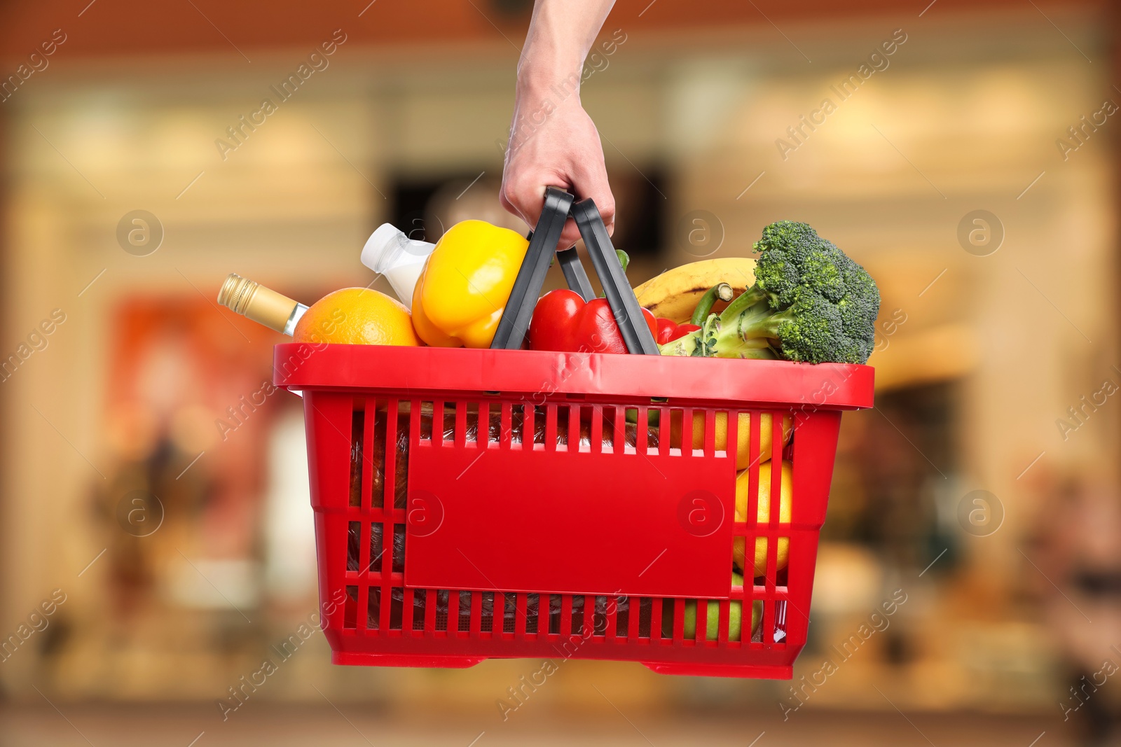 Man holding shopping basket with different food products at supermarket, closeup Image of Man holding shopping basket with different food products at supermarket, closeup