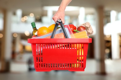 Image of Man holding shopping basket with different food products at supermarket, closeup
