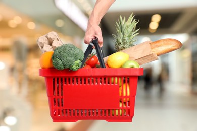 Image of Man holding shopping basket with different food products at supermarket, closeup
