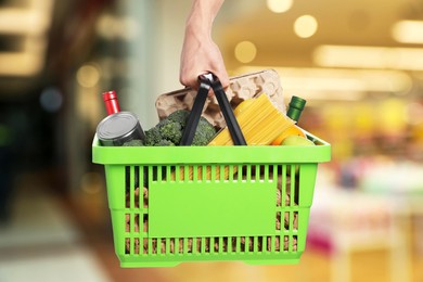 Image of Man holding shopping basket with different food products at supermarket, closeup