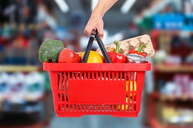 Image of Man holding shopping basket with different food products at supermarket, closeup