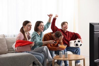 Photo of Emotional football fans watching game together indoors