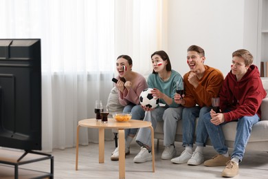 Photo of Emotional football fans watching game together indoors