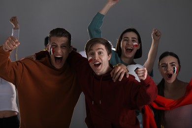 Photo of Emotional sports fans watching game together indoors