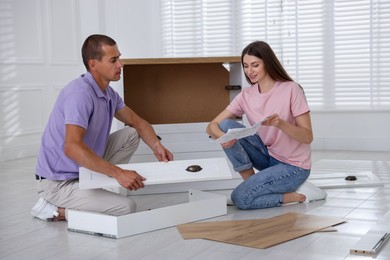 Photo of Couple with manual assembling furniture on floor at home