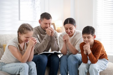 Photo of Family with Bible praying together at home