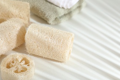 Photo of Different loofah sponges and towels on white table, closeup. Space for text