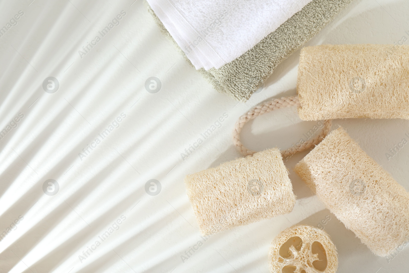 Different loofah sponges and towels on white table, flat lay. Space for text Photo of Different loofah sponges and towels on white table, flat lay. Space for text