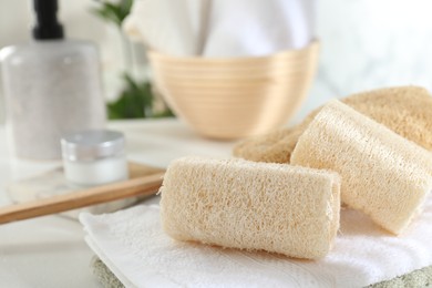 Photo of Different loofah sponges and towels on white table, closeup