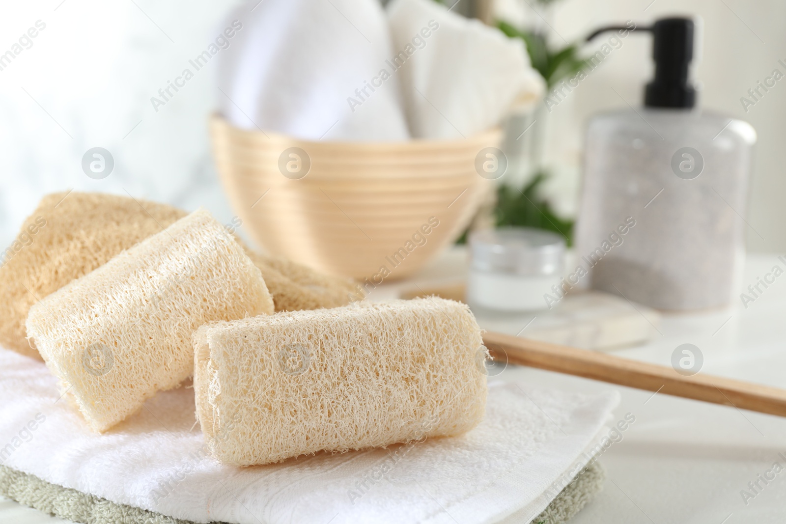 Different loofah sponges and towels on white table, closeup Photo of Different loofah sponges and towels on white table, closeup