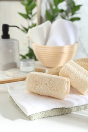 Photo of Different loofah sponges and towels on white table, closeup