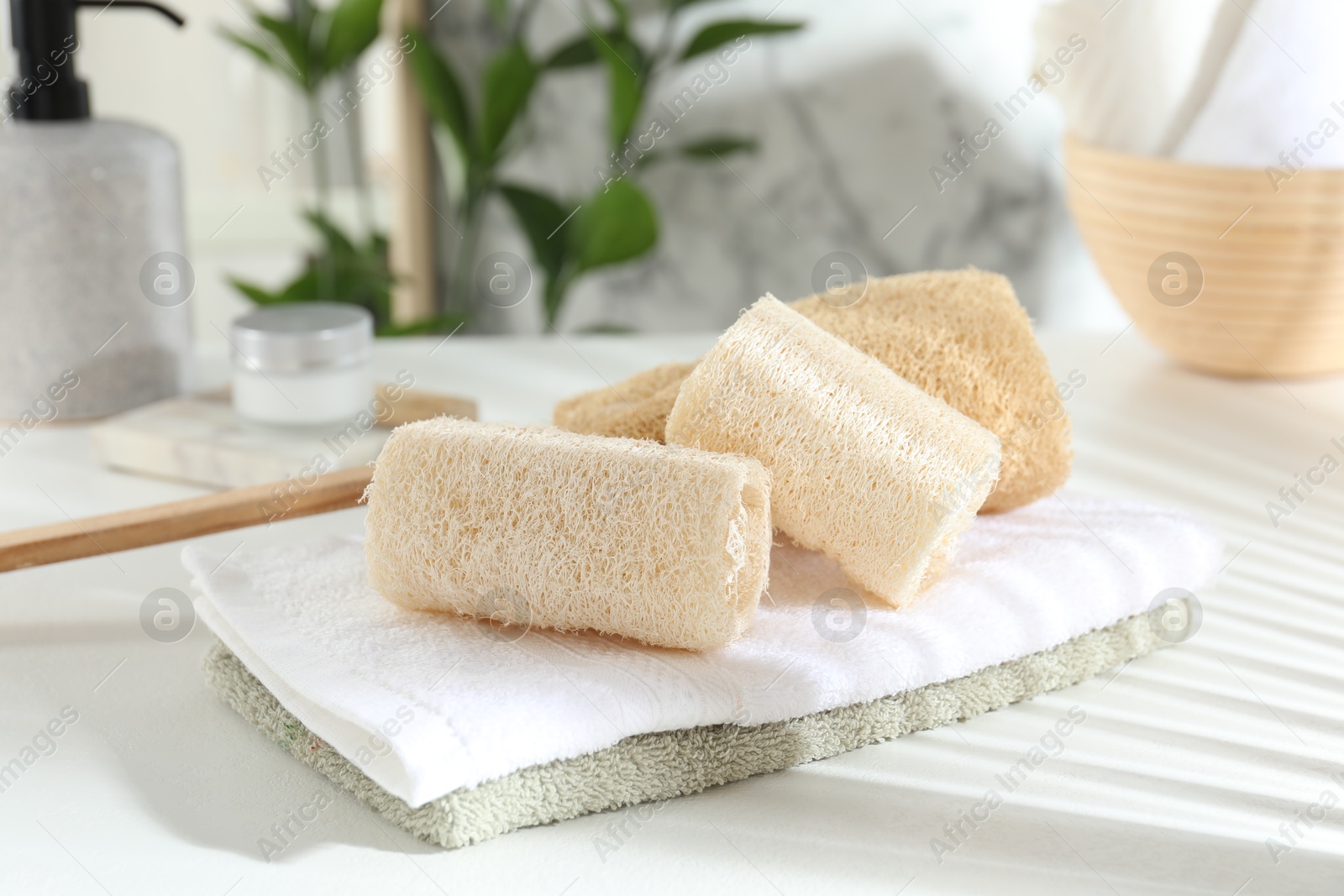 Different loofah sponges and towels on white table, closeup Photo of Different loofah sponges and towels on white table, closeup