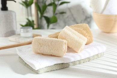 Photo of Different loofah sponges and towels on white table, closeup