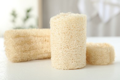Photo of Different loofah sponges on white table, closeup