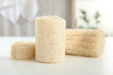 Photo of Different loofah sponges on white table, closeup
