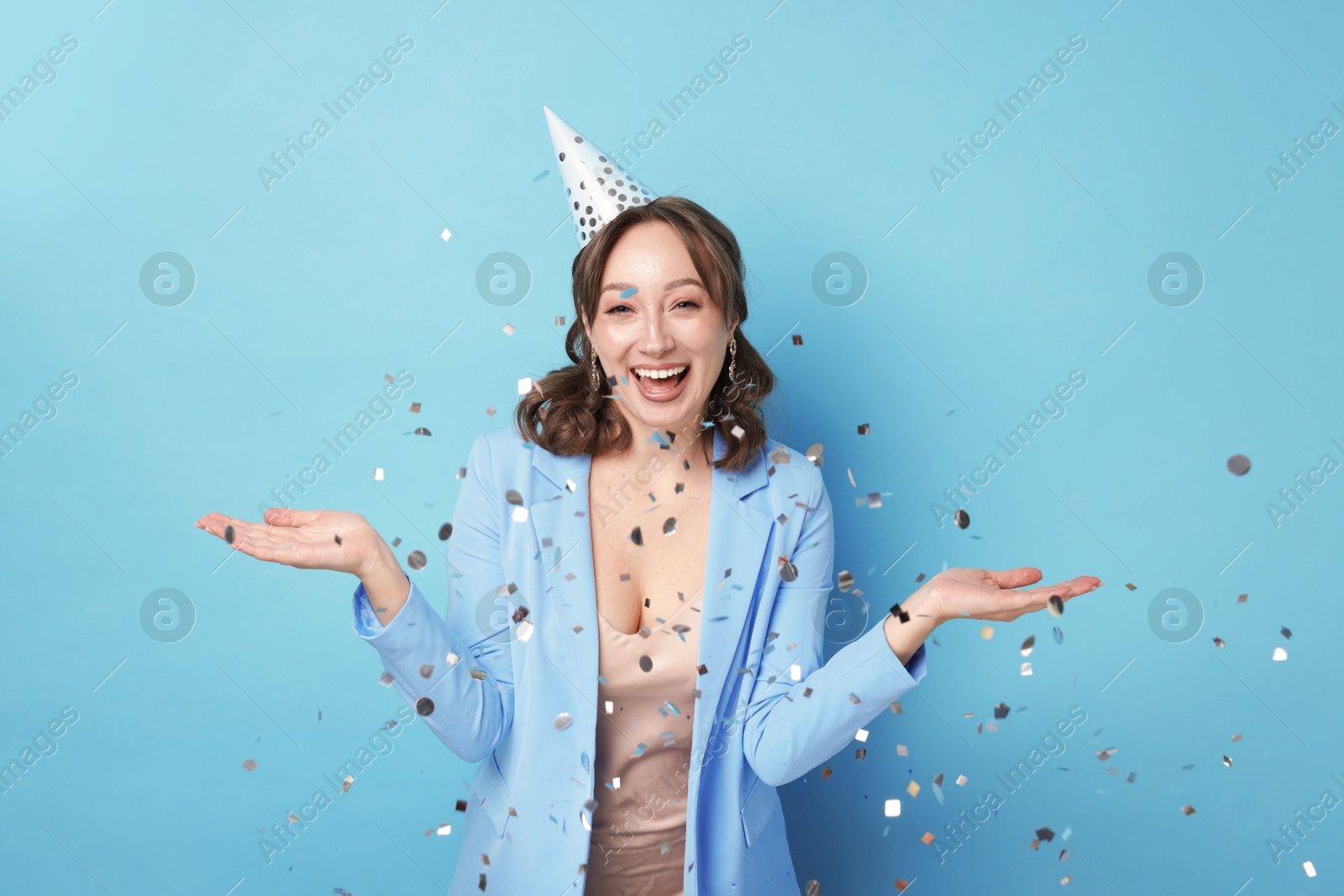 Birthday celebration. Woman on light blue background with confetti Photo of Birthday celebration. Woman on light blue background with confetti