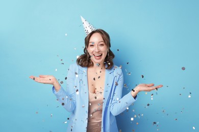 Photo of Birthday celebration. Woman on light blue background with confetti