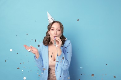Photo of Birthday celebration. Woman with party horn and confetti on light blue background