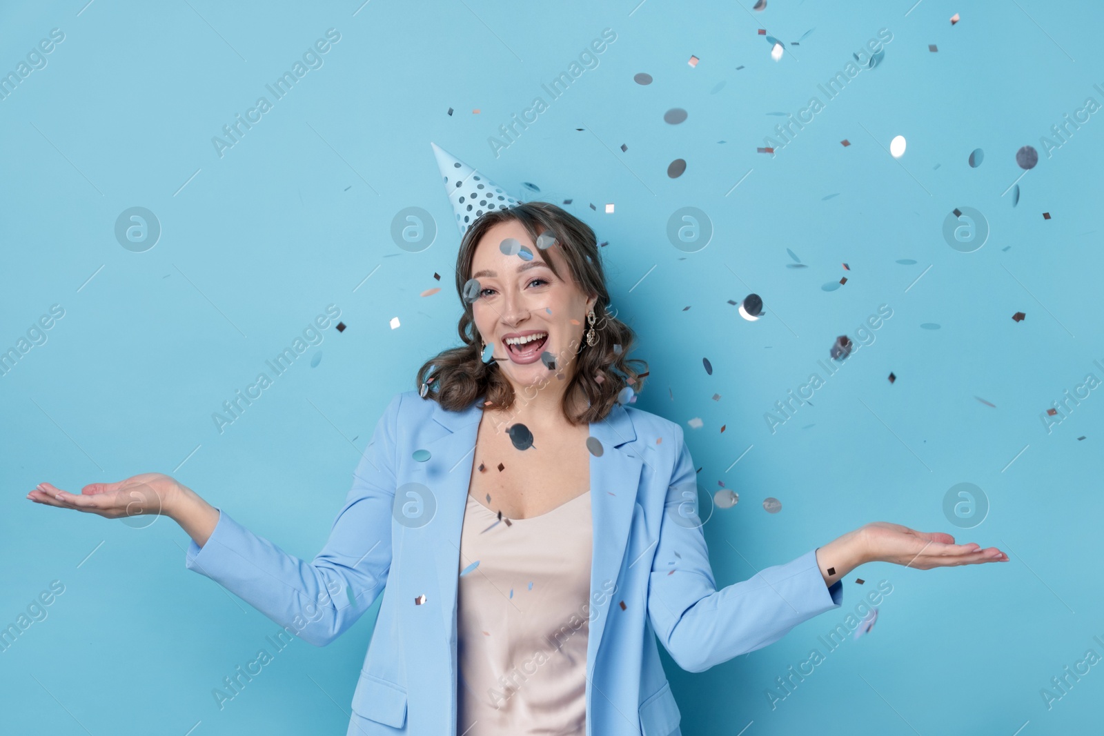 Birthday celebration. Woman on light blue background with confetti Photo of Birthday celebration. Woman on light blue background with confetti