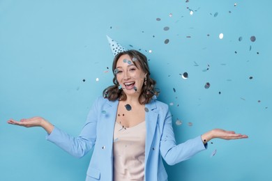 Photo of Birthday celebration. Woman on light blue background with confetti