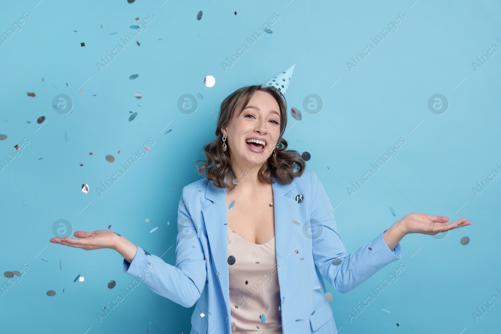 Birthday celebration. Woman on light blue background with confetti Photo of Birthday celebration. Woman on light blue background with confetti