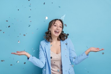 Photo of Birthday celebration. Woman on light blue background with confetti