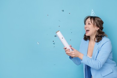 Photo of Birthday celebration. Woman with party popper on light blue background. Space for text