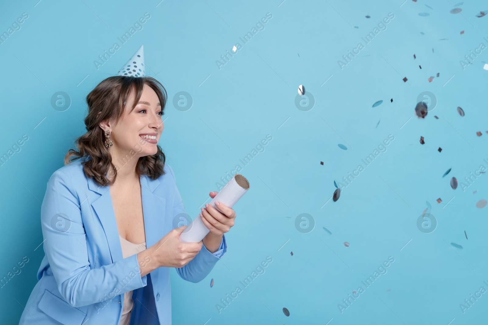 Birthday celebration. Woman with party popper on light blue background Photo of Birthday celebration. Woman with party popper on light blue background