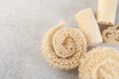 Photo of Different loofah sponges on light grey table, flat lay. Space for text