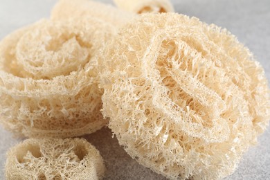 Photo of Different loofah sponges on light grey table, closeup