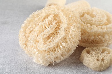 Photo of Different loofah sponges on light grey table, closeup