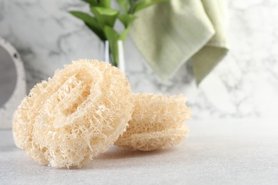 Photo of Different loofah sponges on light grey table, closeup. Space for text