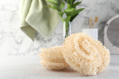 Photo of Different loofah sponges on light grey table, closeup. Space for text