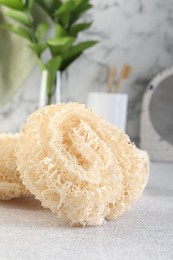 Photo of Different loofah sponges on light grey table, closeup