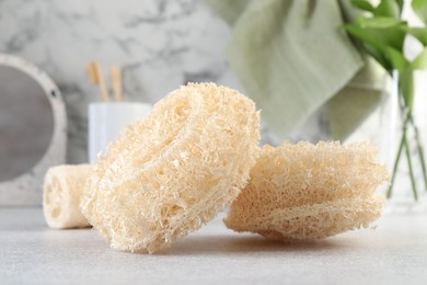 Photo of Different loofah sponges on light grey table, closeup