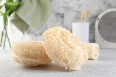 Photo of Different loofah sponges on light grey table, closeup