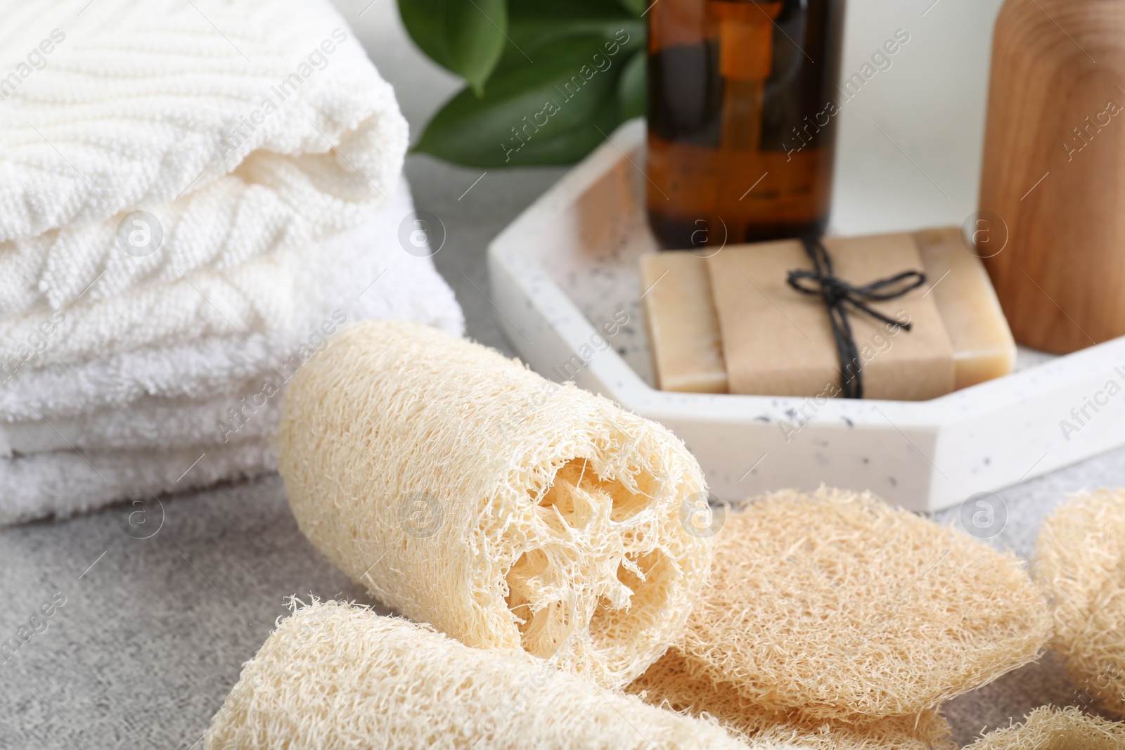 Different loofah sponges, towels and cosmetic products on light grey table, closeup Photo of Different loofah sponges, towels and cosmetic products on light grey table, closeup