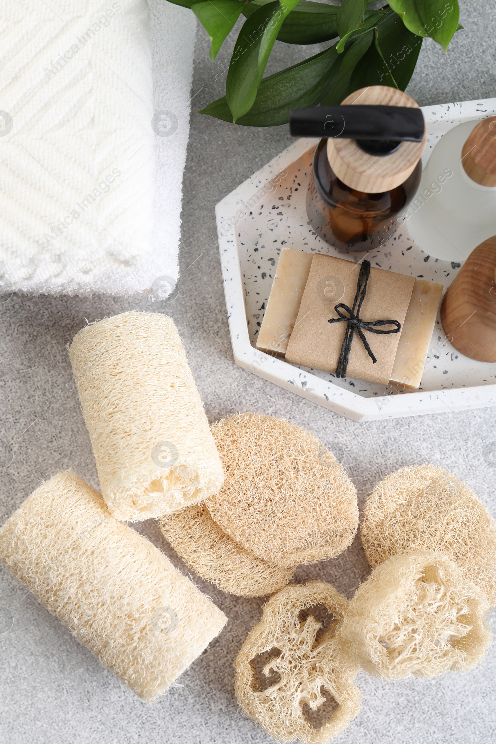 Different loofah sponges, towels and cosmetic products on light grey table, flat lay Photo of Different loofah sponges, towels and cosmetic products on light grey table, flat lay