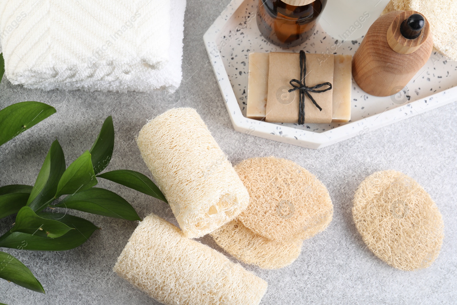 Different loofah sponges, towels and cosmetic products on light grey table, flat lay Photo of Different loofah sponges, towels and cosmetic products on light grey table, flat lay