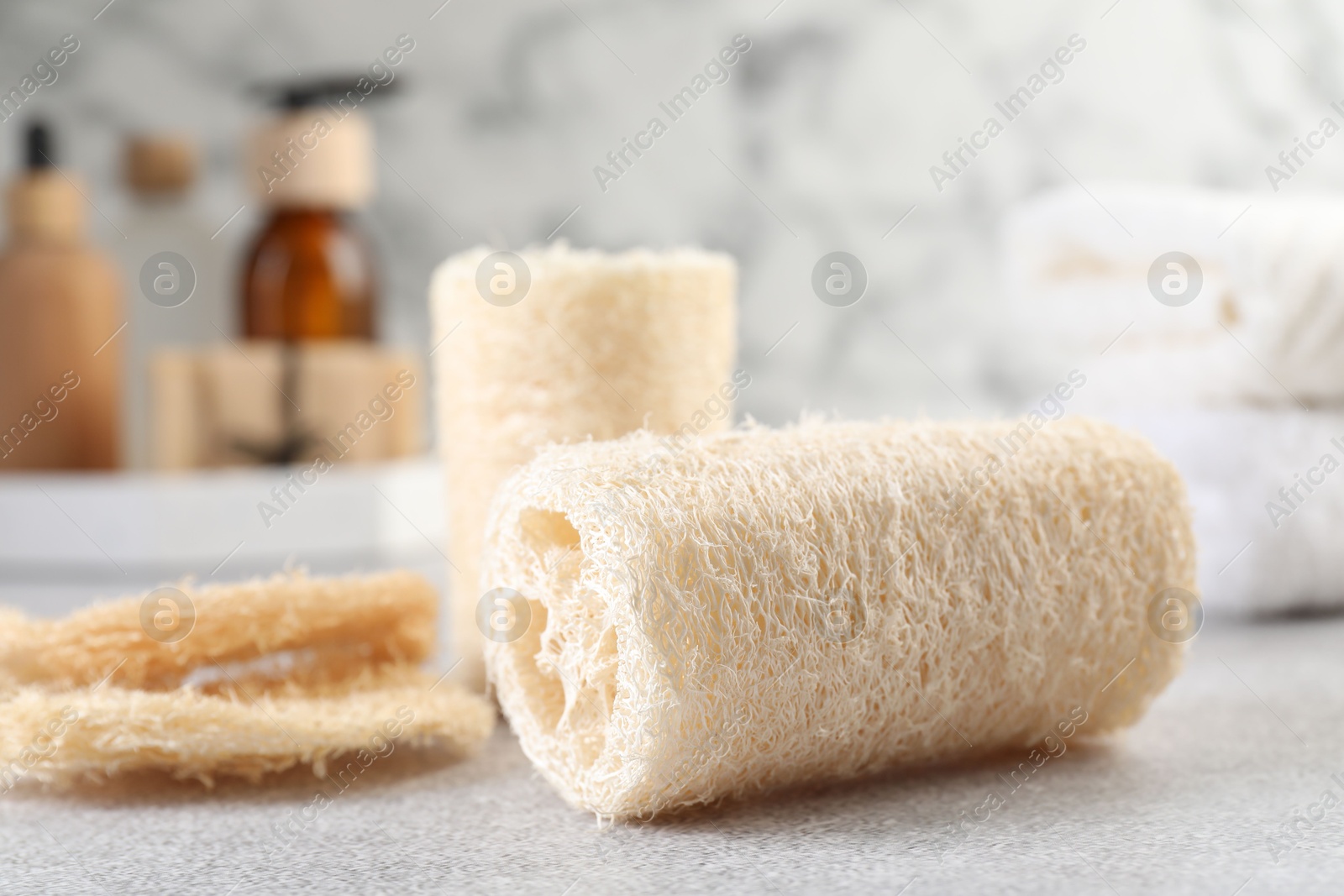 Different loofah sponges and cosmetic products on light grey table, closeup Photo of Different loofah sponges and cosmetic products on light grey table, closeup