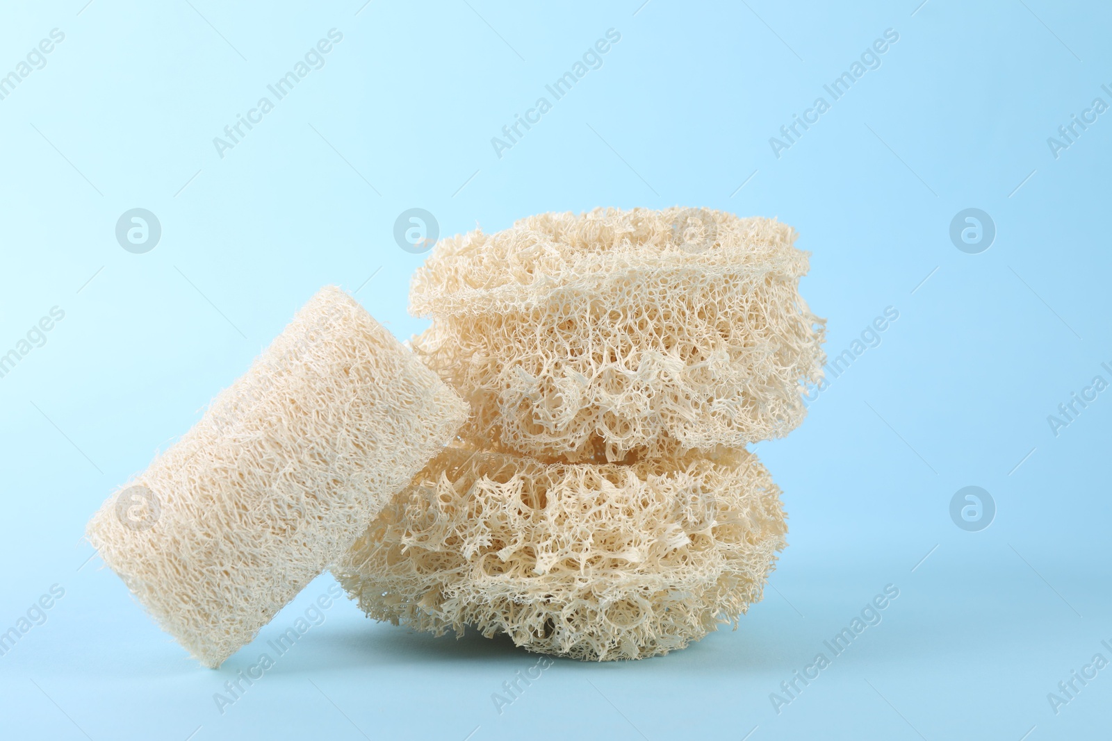 Different loofah sponges on light blue background, closeup Photo of Different loofah sponges on light blue background, closeup