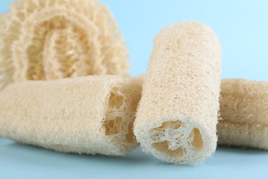 Photo of Different loofah sponges on light blue background, closeup
