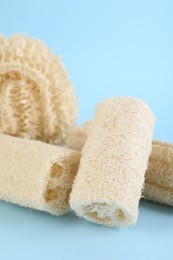 Photo of Different loofah sponges on light blue background, closeup
